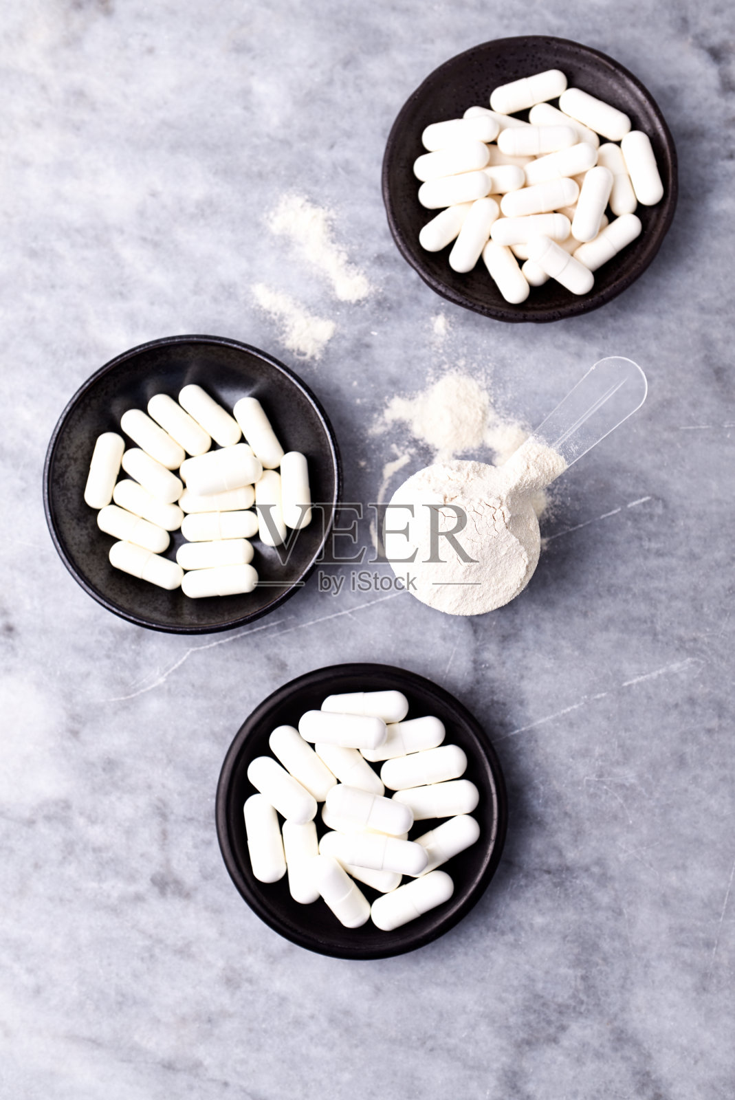 乳清蛋白,水解膠原I型,l -脯氨酸和l -賴氨酸膠囊勺。補充膠原蛋白的生產。明亮的石頭背景。直接上圖。副本的空間。